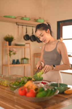 Genç bir kadın mutfağında taze brokoli ve sebze hazırlıyor, günlük hayatta sağlıklı beslenme ve sağlıklı yaşam için teşvik ediyor..
