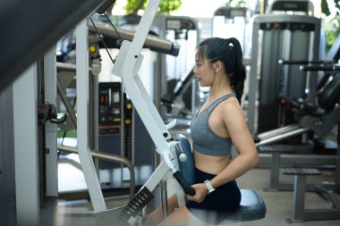 Spor salonunda sırt kaslarını çalıştıran atletik bir kadın..