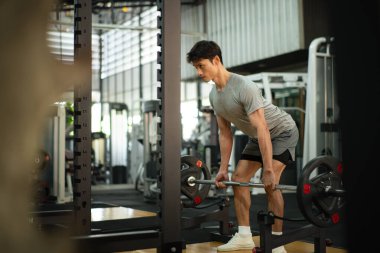 Spor salonunda halterleri kaldıran ciddi bir adamın fotoğrafı..