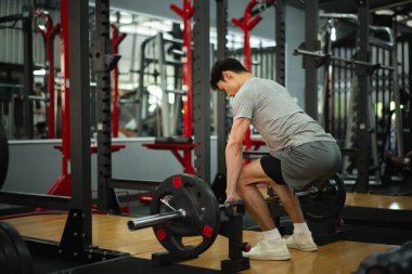 Spor salonunda halterleri kaldıran ciddi bir adamın fotoğrafı..