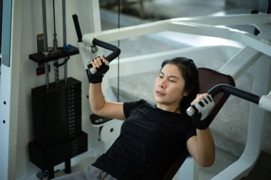 Beden eğitimi makinesinde göğüs presi yapan kadın..