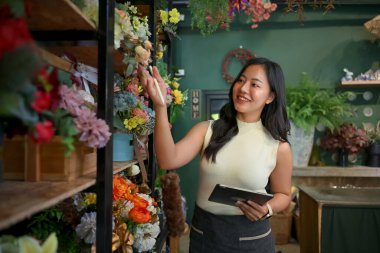 Çiçekçi işyeri sahibi dükkanında dijital tabletle çiçek stoğunu yönetiyor..