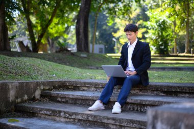 Ofisten bir adam dışarıda merdivenlerde sakin ve odaklanmış bir laptopla oturuyor..