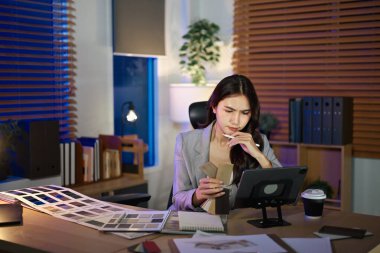 İç mimar kadın şema, kumaş ve kumaş örnekleri ile masada oturuyor..