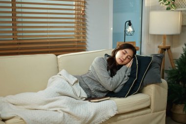 Evdeki kanepede dinlenen genç bir kadın..