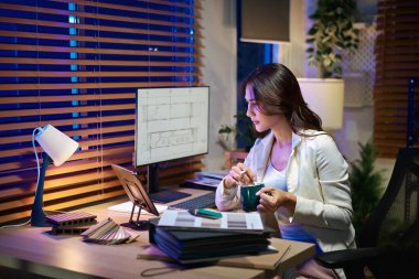 Dijital tablet üzerinde çalışan, örneklerden malzeme ve renk seçen mimar iç tasarımcı.