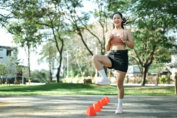 Hız ve çeviklik konisi tatbikatı yapan bir kadın açık havada egzersiz yapıyor..
