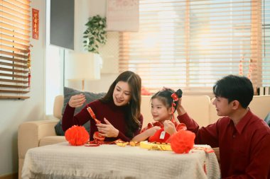 Asyalı aile birlikte oturup Çin Yeni Yılı için kırmızı fenerleri süsleyerek neşeli bir aile anını paylaşıyor..
