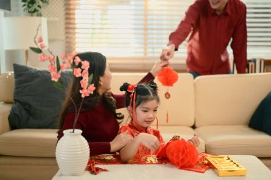 Mutlu aile evi Çin Yeni Yılı için süslerken baba anne ve kızına kırmızı bir süs verdi..