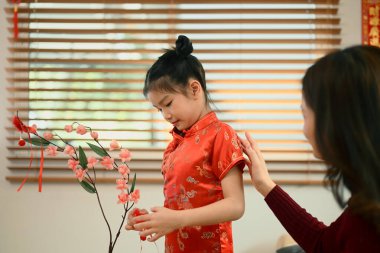 Anne ve kızı, Çin Yeni Yılı için kırmızı kayısı çiçeği süslemişler..