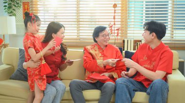 Asyalı büyükanne ve büyükbaba, Çin Yeni Yıl Aile Toplantısı 'nda torunlarına kırmızı zarf veriyorlar..