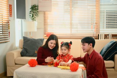 Asyalı aile birlikte oturup Çin Yeni Yılı için kırmızı fenerleri süsleyerek neşeli bir aile anını paylaşıyor..
