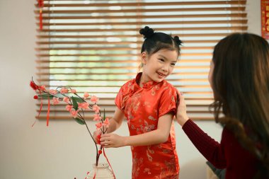 Anne ve kızı, Çin Yeni Yılı için kırmızı kayısı çiçeği süslemişler..