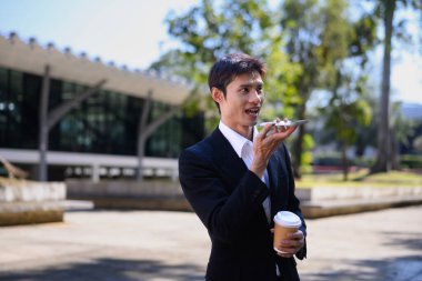 Ofisten bir adam elinde kahve fincanıyla dışarıda telefonla konuşuyor..