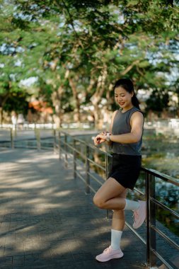 Koşu sırasında duraklayan kadınlar, parkta akıllı bir şekilde spor yapma sürecini kontrol ediyorlar..