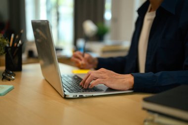 Kırpılmış çekim adamı yapışkan notlara yazıyor ve modern bir çalışma alanında dizüstü bilgisayar kullanıyor, çoklu görev konsepti ile.