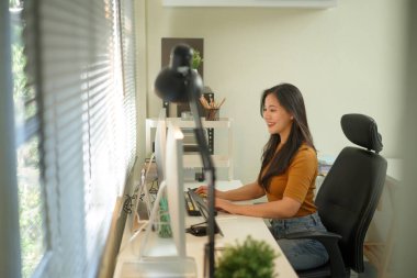 Stüdyosunda dizüstü bilgisayarla çalışan yaratıcı genç bir kadın..