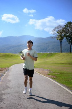 Sporcu park ve dağ manzarasında arka planda koşuyor, Yeni Yıl Sağlık Hizmetleri.