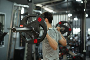 Kapalı halter Bir adam çömeliyor ve ağırlık kaldırıyor.