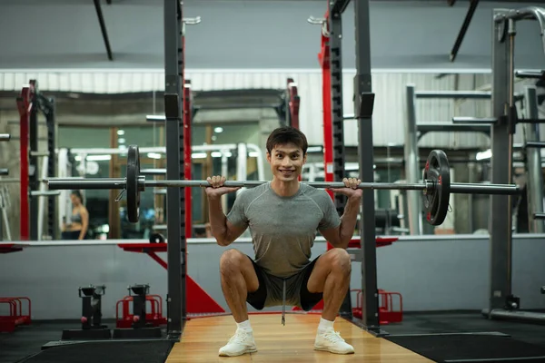 Çömelip ağırlık kaldıran bir adam..