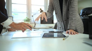 Bir masadaki belge ve dijital verileri tartışan, takım çalışmasını, karar verme mekanizmasını ve bir ofiste profesyonel işbirliğini gösteren iş arkadaşlarının yakın çekimleri.