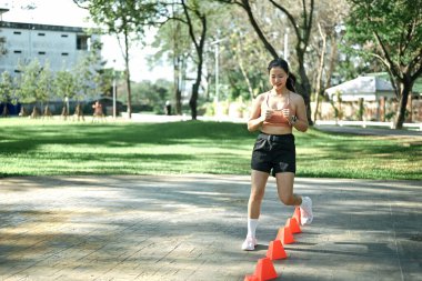 Hız ve çeviklik konisi tatbikatı yapan bir kadın açık havada egzersiz yapıyor..