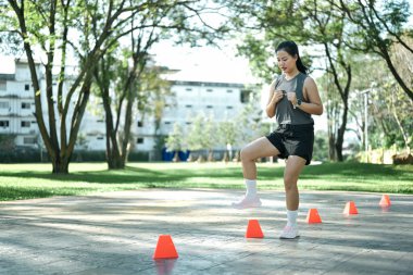 Hız ve çeviklik konisi tatbikatı yapan bir kadın açık havada egzersiz yapıyor..