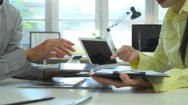İş görüşmeleri sırasında tablet ve laptop kullanarak bilgi alışverişinde bulunan iş arkadaşları, veri paylaşımı, takım çalışması ve profesyonel.