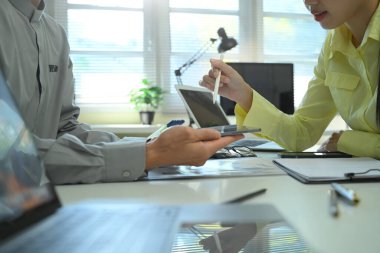 İş görüşmeleri sırasında tablet ve laptop kullanarak bilgi alışverişinde bulunan iş arkadaşları, veri paylaşımı, takım çalışması ve profesyonel.