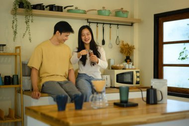 Genç bir çift sıcak bir ev mutfağında kahkahalarla kahkaha atıyor..