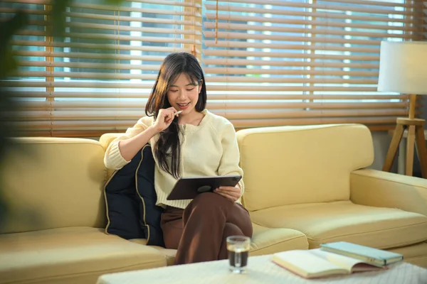 Oturma odasındaki kanepede dijital tablet kullanan kadın..