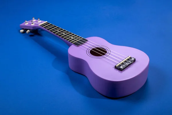 Four string ukulele guitar on blue background