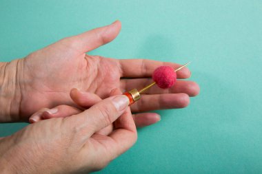 Bir kadın, bir şey yaparken yün yumağını bir çöp tenekesiyle deliyor.