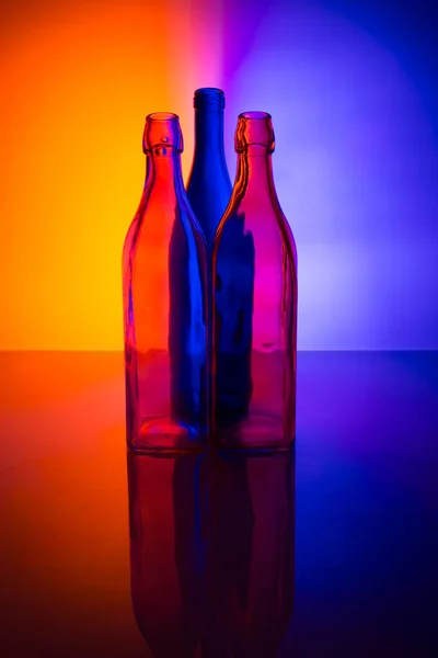 Stilleven Met Gekleurde Glazen Flessen Een Gekleurde Achtergrond — Stockfoto