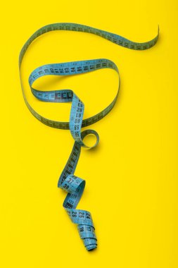 Sarı arka planda terzi mezurası var.