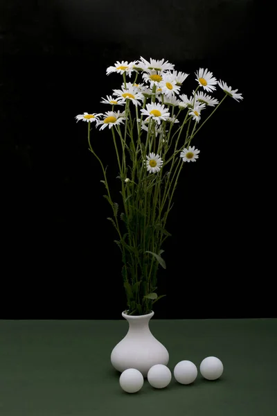Csendélet Százszorszépekkel Vázában Fehér Golyókkal Zöld Asztalon — Stock Fotó