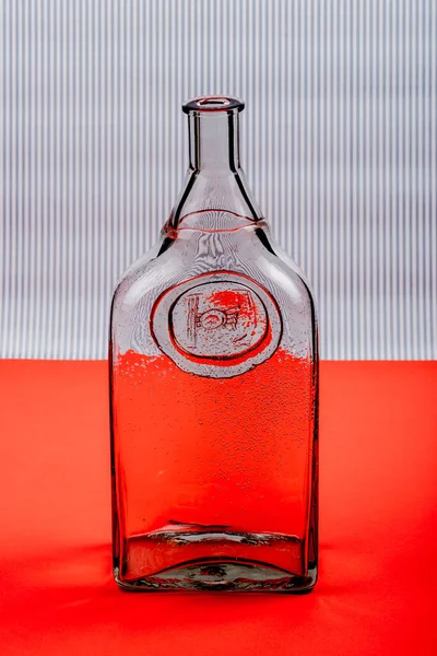 Glazen Transparante Fles Rode Tafel Gestreepte Achtergrond — Stockfoto