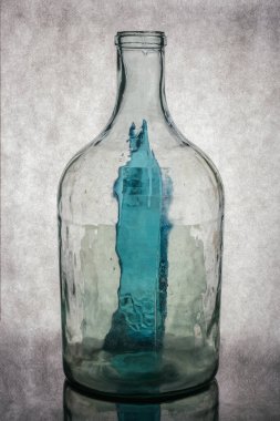 Gri arka planda şeffaf cam bir şişeyle