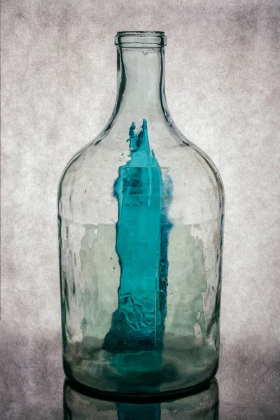 Gri arka planda şeffaf cam bir şişeyle