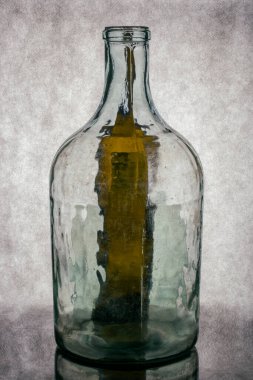 Gri arka planda şeffaf cam bir şişeyle