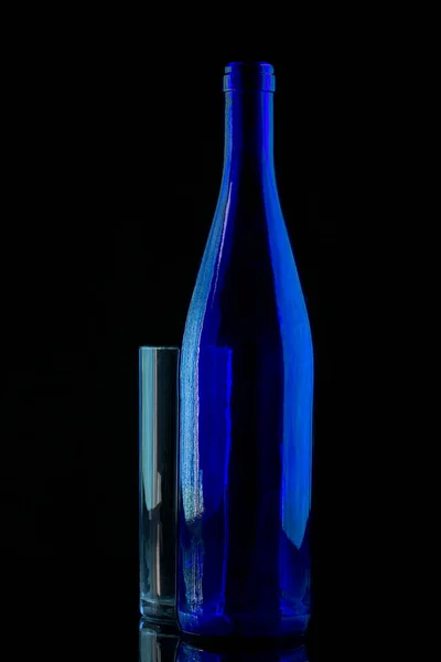 黒を基調としたブルーボトルとガラスの静物画 — ストック写真