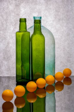 Yansıtıcı yüzeyde renkli şişeler ve turuncu toplarla dolu bir hayat