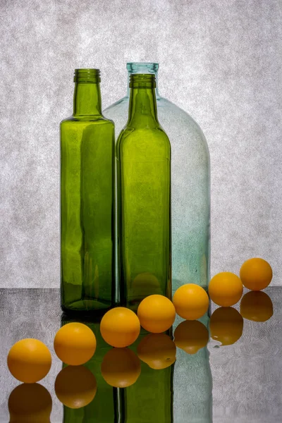 反射面に色のついたボトルとオレンジのボールで静物画 — ストック写真