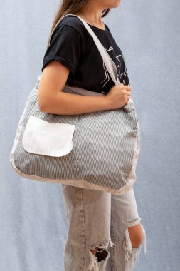 Bir kız elinde doğal kumaştan yapılmış tekrar kullanılabilir bir Eko Poşet tutuyor.