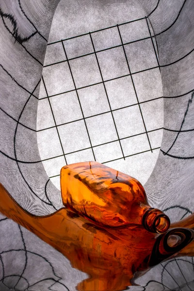 Abstract still life with orange glass bottle and its reflection