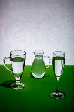 Masadaki gri-yeşil arka planda cam eşyalar