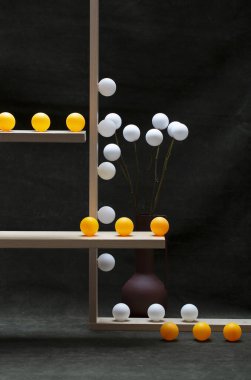 Beyaz vazolar ve tahta raflarda beyaz ve turuncu toplarla dolu bir hayat.