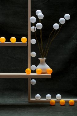 Beyaz vazolar ve tahta raflarda beyaz ve turuncu toplarla dolu bir hayat.