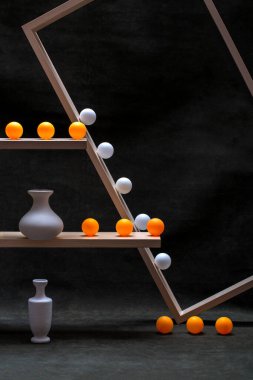 Beyaz vazolar ve tahta raflarda beyaz ve turuncu toplarla dolu bir hayat.