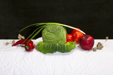 Savoy lahanası, sebzeler ve meyvelerle dolu beyaz bir masa örtüsü